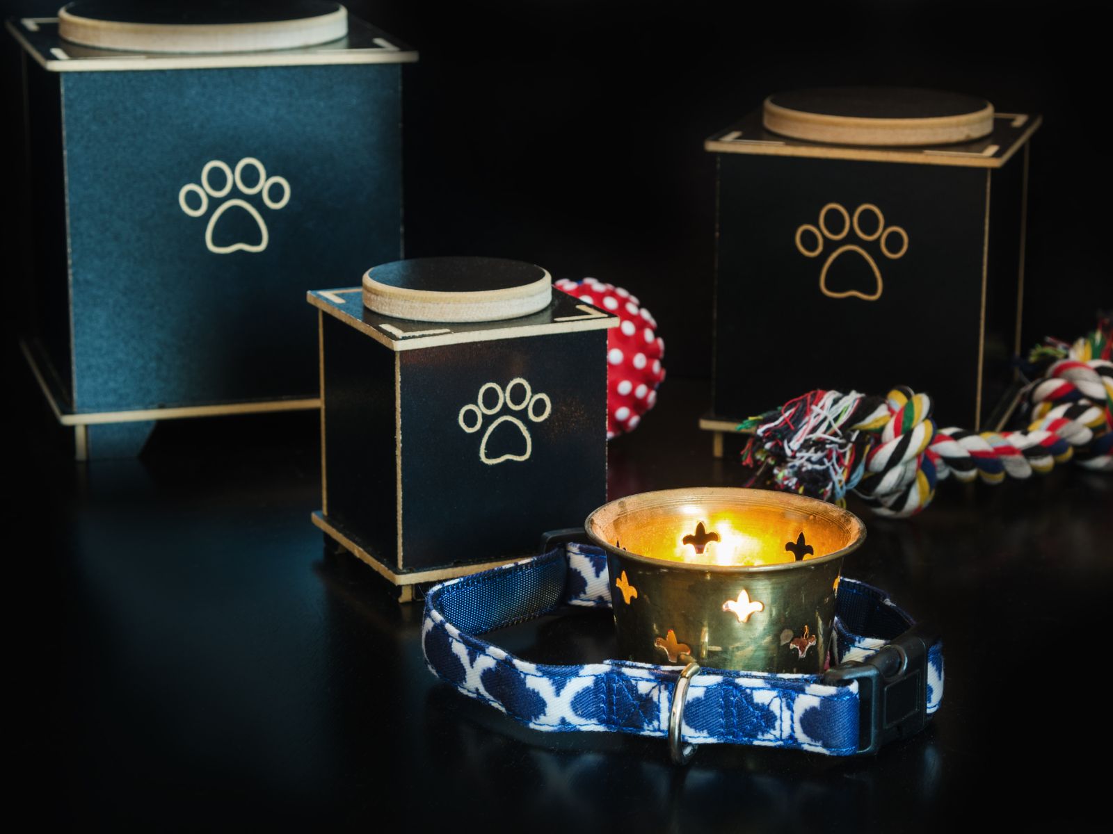 A candle beside a dog collar and a paw print